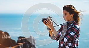 Tourist traveler photographer making pictures sea scape on photo camera on background ocean, hipster girl looking on nature horizo