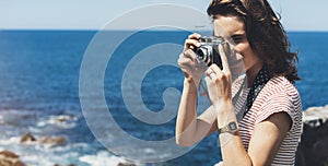 Tourist traveler photographer making pictures sea scape on vintage photo camera on background yacht and boat piar, hipster girl