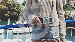 Tourist traveler photographer making pictures sea scape on vintage photo camera on background yacht and boat piar photo