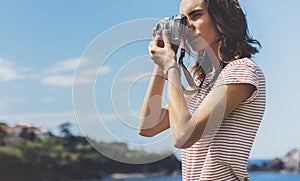 Tourist traveler photographer making pictures seascape on vintage photo camera on background yacht and boat, hipster girl enjoy