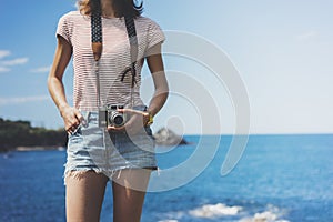 Tourist traveler photographer making pictures seascape on vintage photo camera on background yacht and boat piar, hipster girl