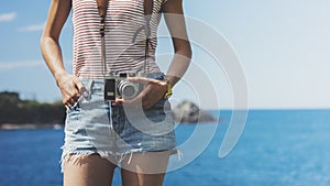 Tourist traveler photographer making pictures seascape on vintage photo camera on background yacht and boat piar, hipster girl