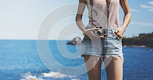 Tourist traveler photographer making pictures seascape on vintage photo camera on background yacht and boat piar, hipster girl enj