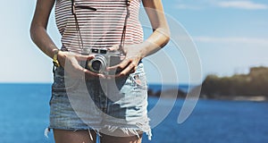 Tourist traveler photographer making pictures seascape on vintage photo camera on background yacht and piar, hipster girl enjoy