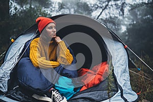 Tourist traveler ralaxing in camp tent in foggy rain forest, closeup lonely hiker woman enjoy mist nature trip, green trekking