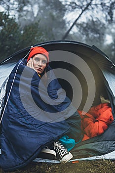 Tourist traveler ralaxing in camp tent in froggy rain forest, closeup lonely hiker woman enjoy mist nature trip, green trekking