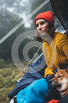 Tourist traveler relaxation red shiba inu in camp tent on background blue froggy forest, closeup hiker woman with puppy in mist