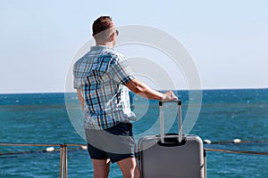 Tourist and traveler is stand on beach of hotel resort with traveled suitcase, enjoys view sea environment, nature landscape.