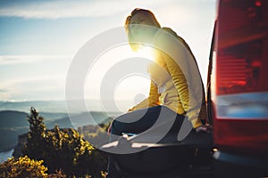 Tourist traveler traveling in car on green top on mountain, young girl smiles happily against background sunset in the mountains h