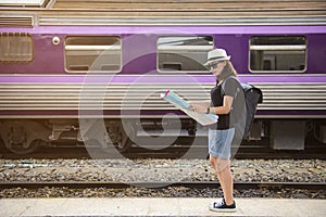 Tourist traveler woman backpack looking a map at a train station