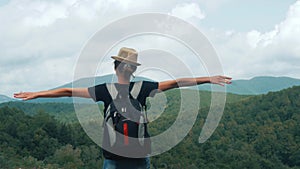 Tourist traveler young girl with backpack standing on top of the mountain and enjoying valley view. Happy hiker with her