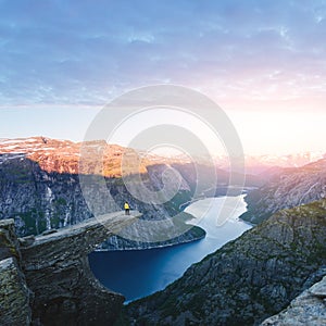 Tourist on Trolltunga rock in Norway mountains