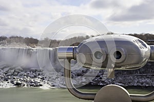 Tourist viewing binoculars at Niagara Falls with american waterfall in background