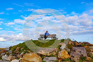 Tourist viewpoint on a hill with senior female hiker sitting next to her dachshund taking a break