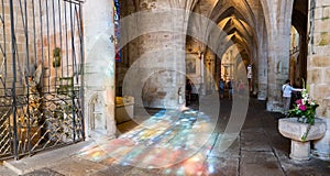 Tourist visit the Basilica de Saint-Saveur in Dinan with reflections of stained glass windows on the stone floor