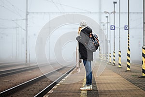 Tourist waiting for train at railroad station in fog