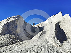 A tourist walkin on the white sandstone cliffs at the Blue Lake at St Bathans in Otago region of the South Island of New Zealand photo