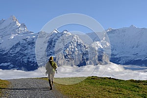 Tourist walking with a backpack in the mountains at Grindewald, Switzerland. Mountain hiking in the high mountains