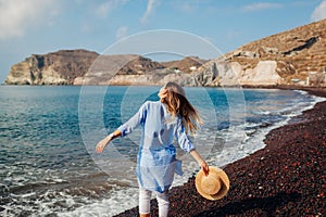 Tourist walking on coastline of Red beach Santorini island Greece enjoying sea landscape. Traveling summer vacation