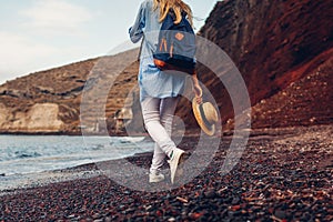 Tourist walking on Red beach on Aegean sea coastline Santorini island, Greece. Woman with backpack traveling