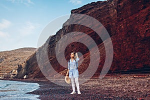 Tourist walking on Red beach on Aegean sea coastline Santorini island, Greece. Woman with backpack traveling