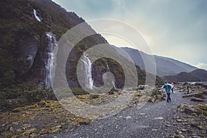 Tourist walking on trail to franz josef glacier in foggy weather