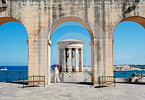 Tourist walking under arches of historical city with view on War siege Memorial