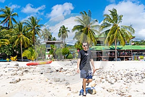 A tourist walks along a sandy tropical beach. Typical vacationer