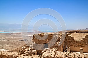 Tourist walks out of structure at Masada with Dead Sea in background