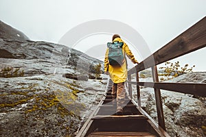 Tourist woman with backpack climbing up stairs in rocky mountains