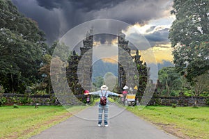 Tourist woman with backpack and hat on vacation walking through the Hindu temple in Bali Indonesia, Handara gate