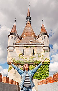 Tourist woman with backpack posing on bridge in front of Vajdahunyad castle in Budapest, Hungary