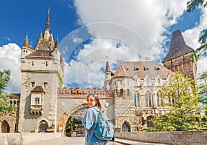 Tourist woman with backpack posing on bridge in front of Vajdahunyad castle in Budapest, Hungary