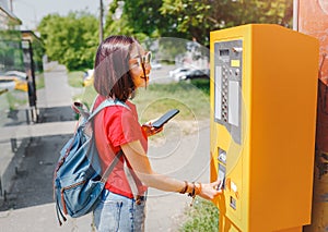 Tourist woman buying a ticket for public transport at the automatic vending machine