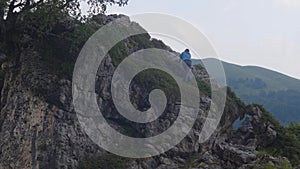 Tourist woman climbing on mountain peak while summer hiking