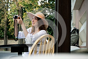 Tourist woman digital camera street cafe terrace girl hat sun vintage travel photo shooting white cup coffee panasonic lumix