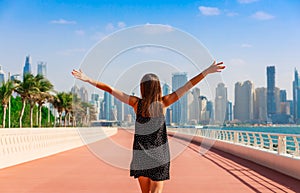 Tourist woman enjoying view of Dubai with palms and skyscrapers. Sunny summer day in Dubai desert. Dubai is famous tourist