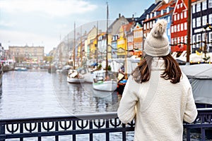 A tourist woman enjoys the view to the beautiful Nyhavn area in Copenhagen
