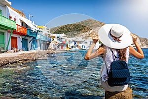 Tourist woman enjoys the view to the fishing village of Klima, Milos, Greece