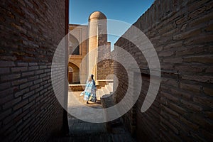 Tourist woman in ethnic dress at narrow street in Ichan Kala of Khiva