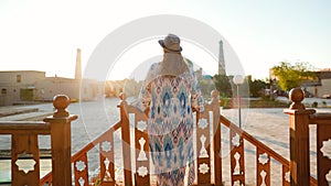 Tourist woman in ethnic dress near mosque in Ichan Kala of Khiva