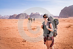 Tourist woman with friends in a desert. Jordan natural park Wadi Rum. Backpacker on the road. Woman hiker with backpack