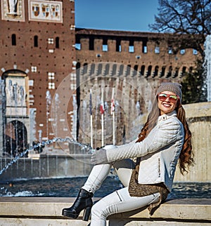 Tourist woman in front of Sforza Castle sitting near fountain