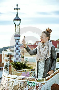 Tourist woman at Guell Park with digital camera taking selfie