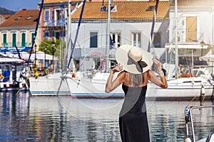 A tourist woman with hat enjoys the view to the marina of Fiskardo, Cephalonia, Greece photo