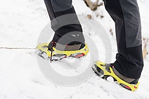 Tourist woman hiking in the snowy mountains. Crampons on shoes.