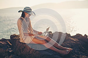 Tourist woman on holidays enjoying online with a laptop on the beach