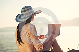 Tourist woman on holidays enjoying online with a laptop on the beach