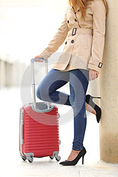 Tourist woman legs waiting with a suitcase in an airport