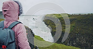 Tourist woman looking at Gullfoss waterfall the famous attraction and landmark destination on Iceland on the Golden